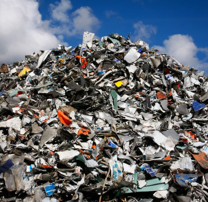 A pile of metal and plastic waste in the middle of a field.